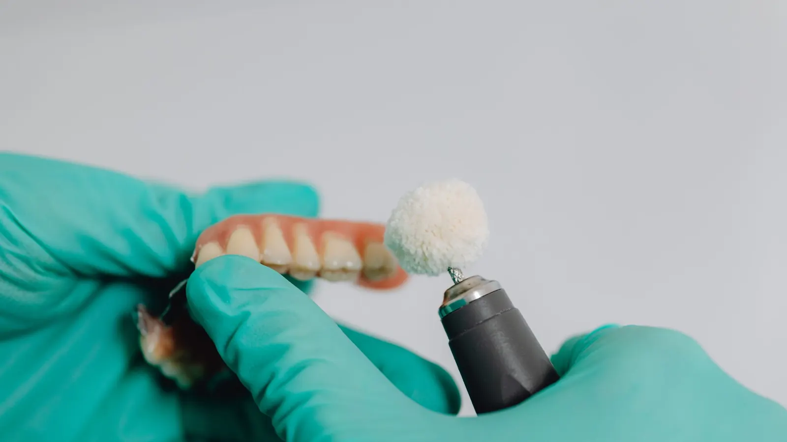 Técnico dental puliendo una dentadura postiza con un cepillo de fieltro en el laboratorio