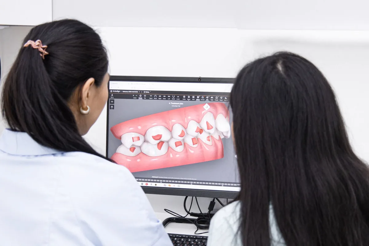 Dos profesionales revisan en la pantalla el modelo digital en 3D de una boca con encía