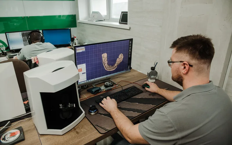 Técnico de laboratorio revisando en pantalla el modelo digital en 3D de una arcada dental
