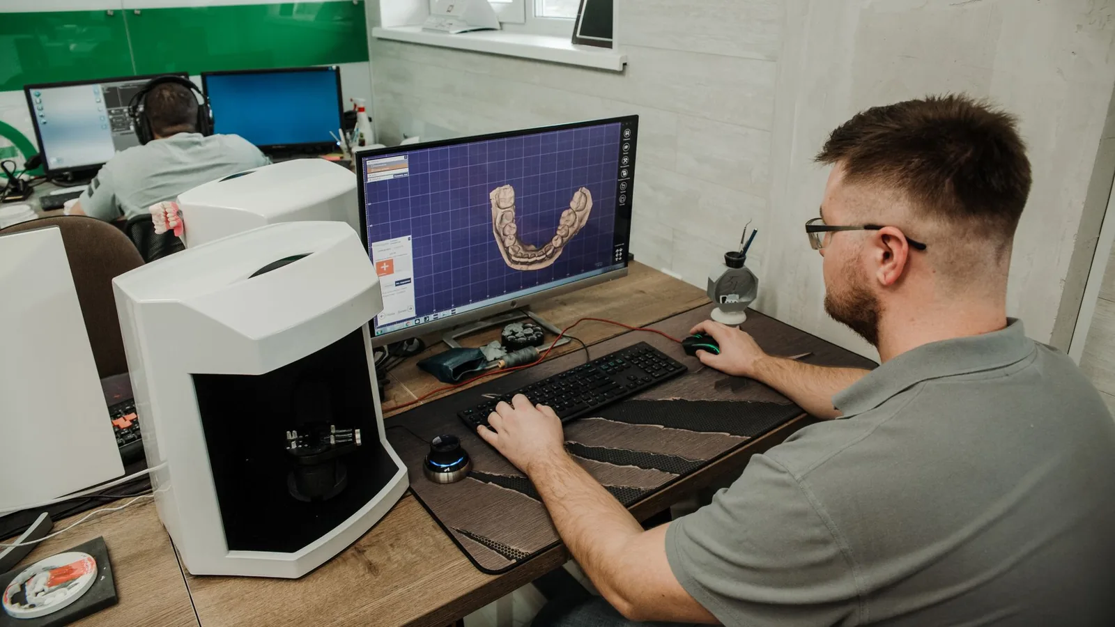 Técnico de laboratorio revisando en pantalla el modelo digital en 3D de una arcada dental