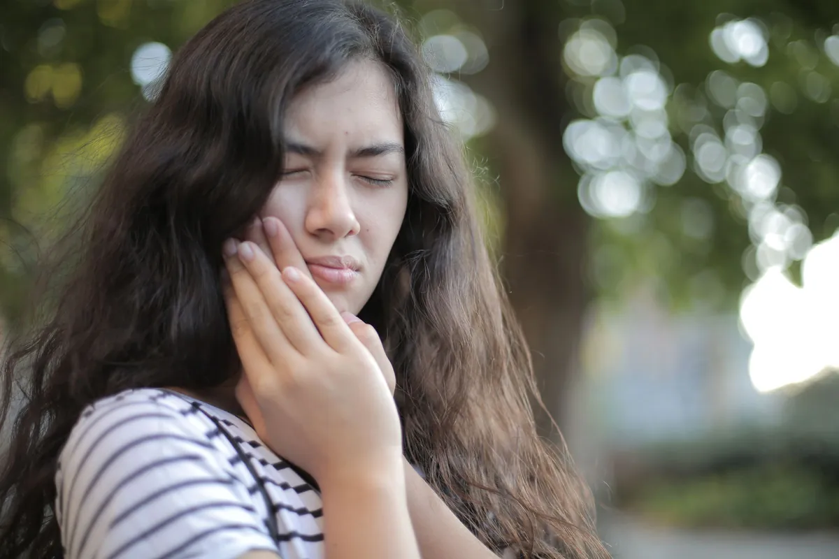 Mujer con dolor en la mandíbula, una de las señales de bruxismo que pueden requerir una férula de descarga