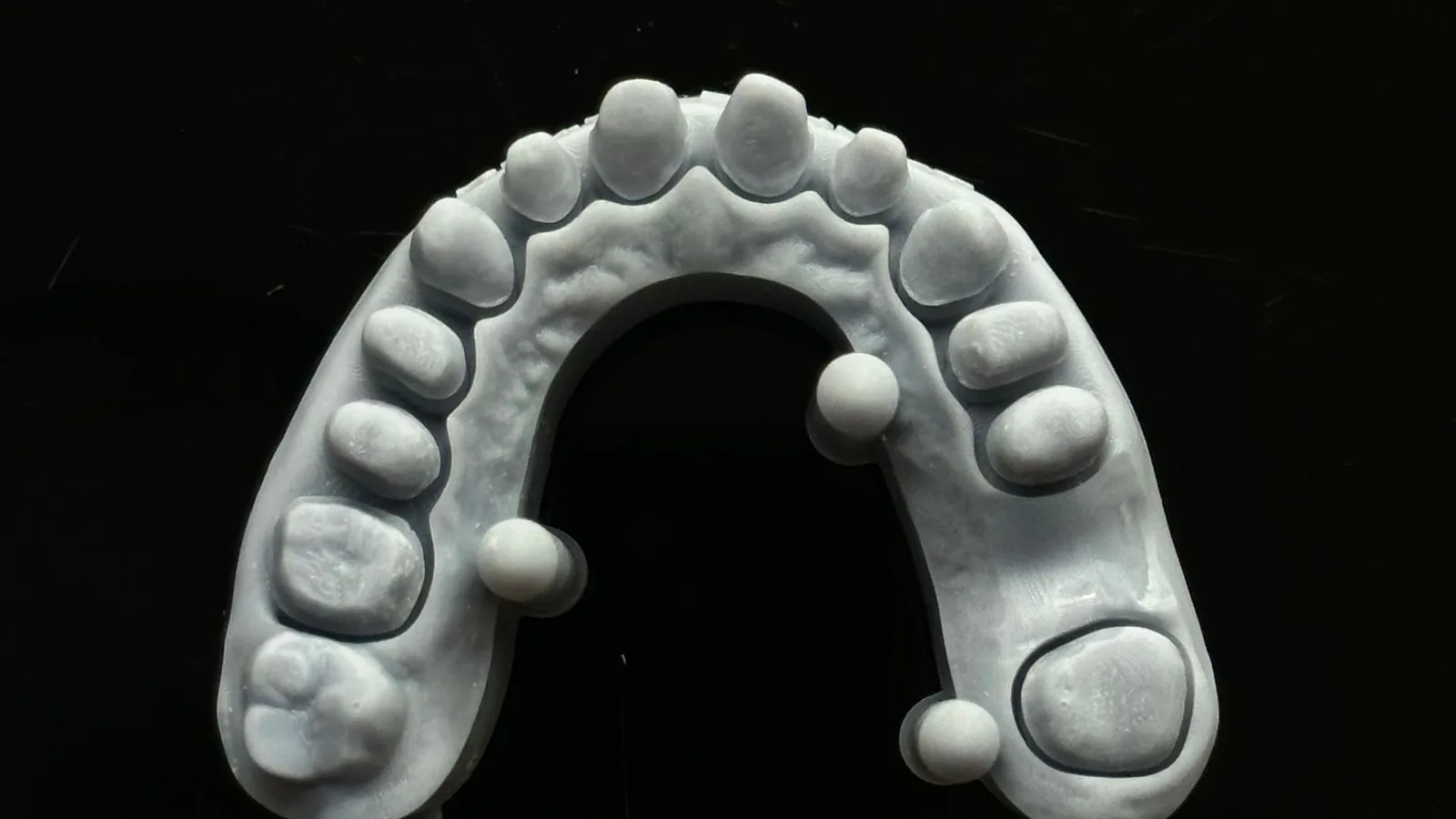 Modelo impreso de una arcada con todos los dientes tallados, con el margen de cada muñón marcado