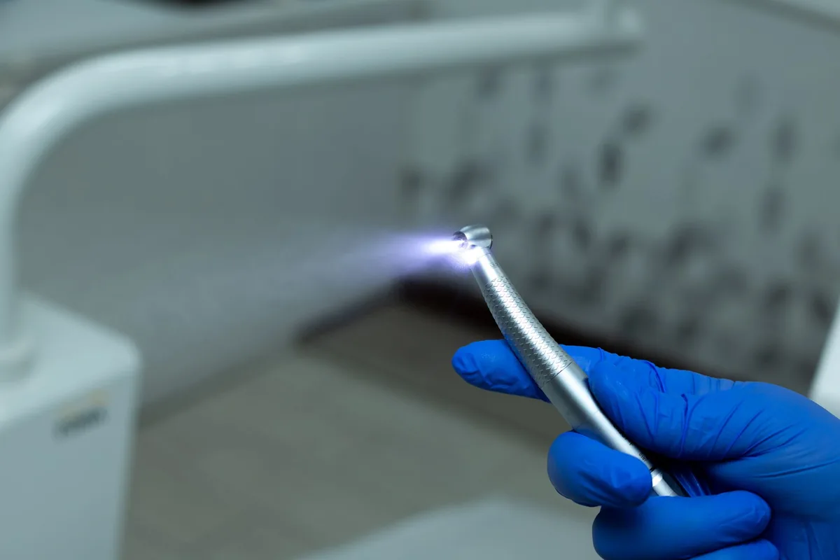 Mano con guante sujetando la turbina dental con la que se talla el diente y se define la línea de terminación