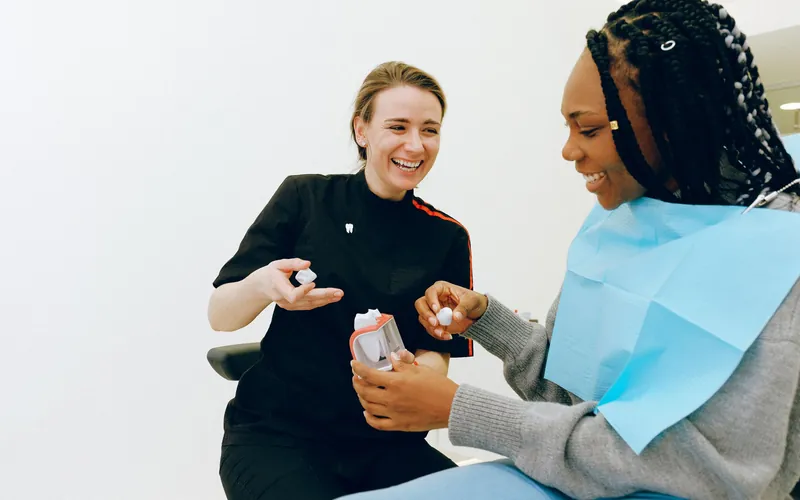 Dentista explicando a una paciente con un modelo dental cómo es una prótesis de acetal removible