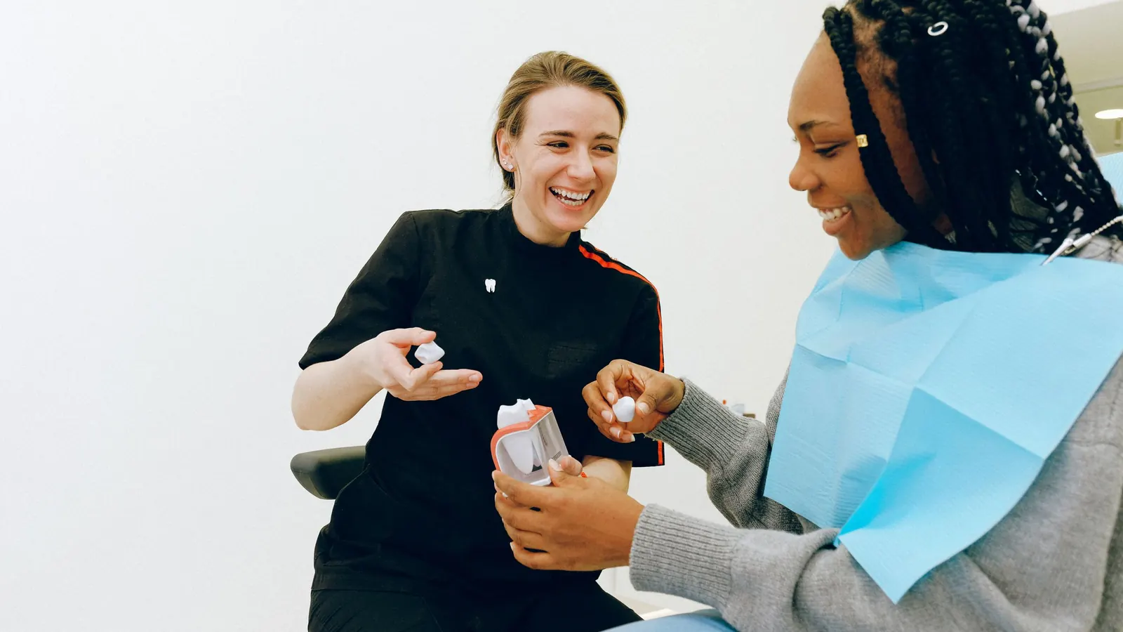 Dentista explicando a una paciente con un modelo dental cómo es una prótesis de acetal removible
