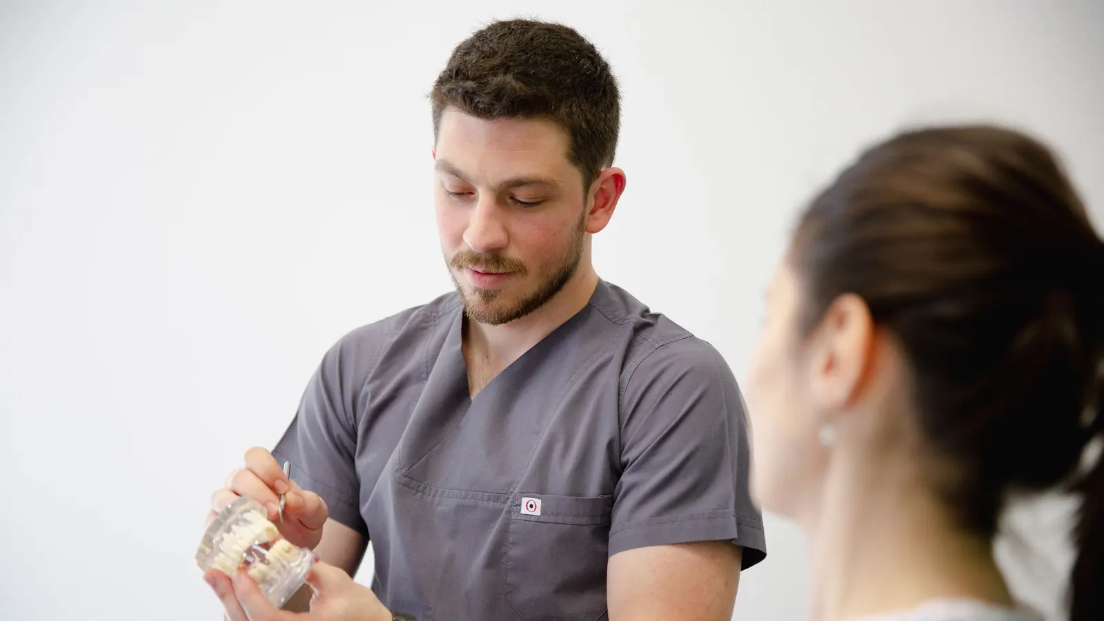 Dentista enseñando un modelo dental a una paciente para decidir entre prótesis dental fija o removible
