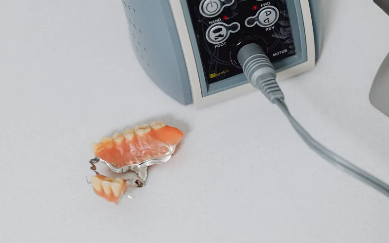 Prótesis esquelética removible con estructura metálica y dientes de resina junto al micromotor del laboratorio