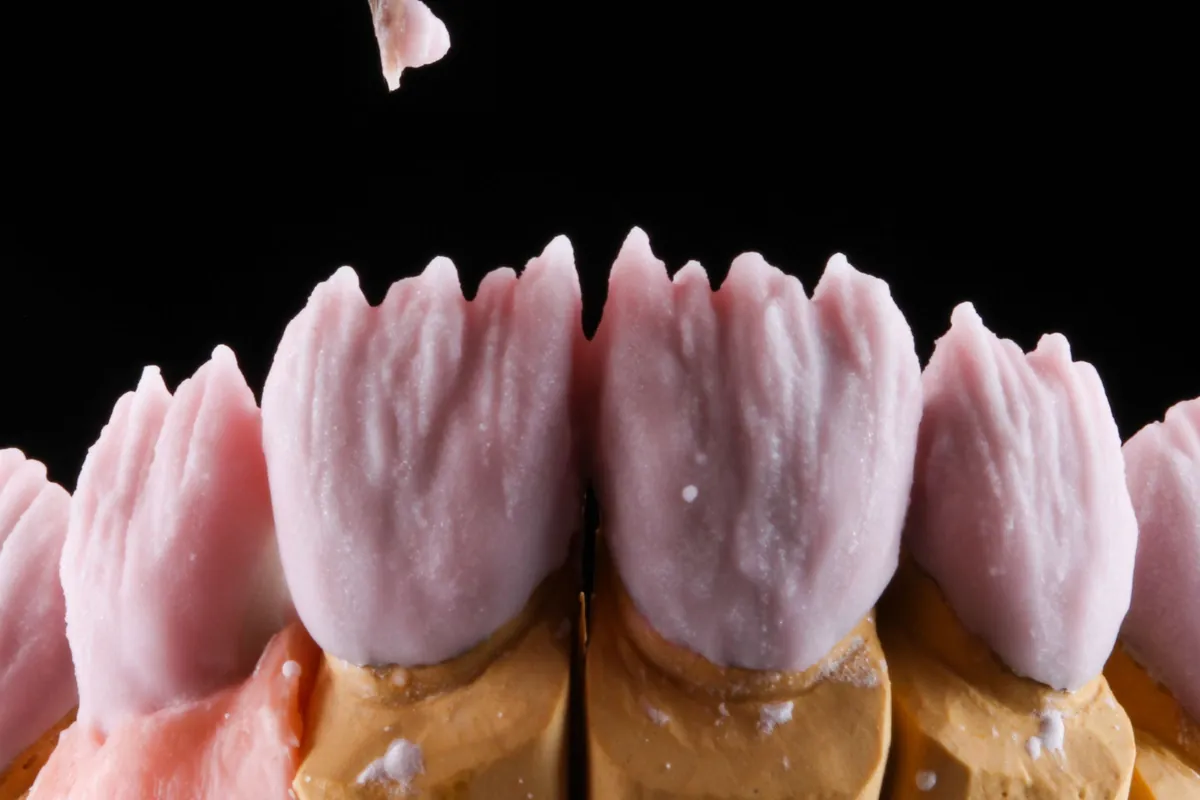 Técnico caracterizando con pincel la encía rosa de una prótesis dental en el laboratorio