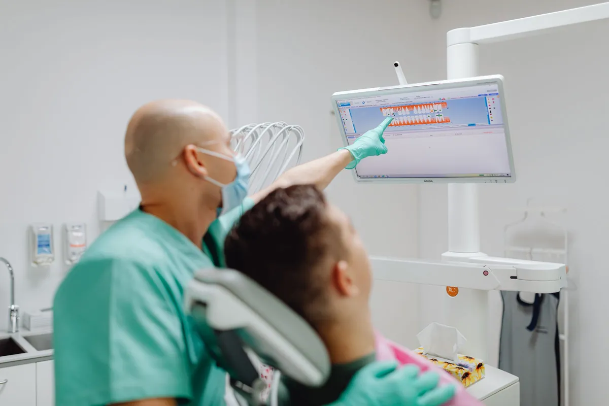Dentista explicando al paciente en la pantalla la planificación de su prótesis provisional
