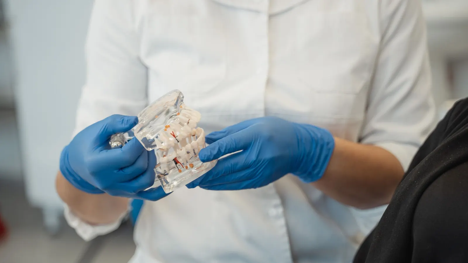 Dentista mostrando en un modelo transparente los implantes que sujetan una sobredentadura