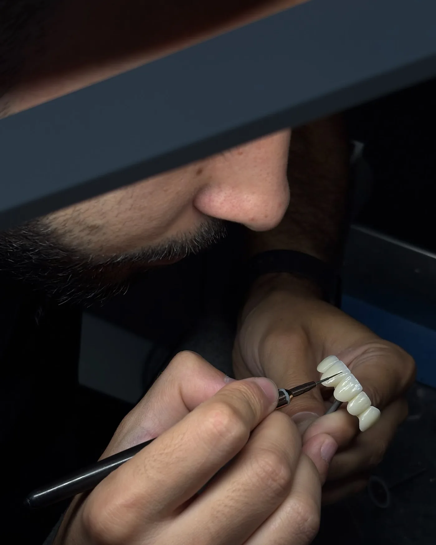 Técnico de PlanoDentaLab caracterizando un puente con pincel en el laboratorio protésico dental de Córdoba